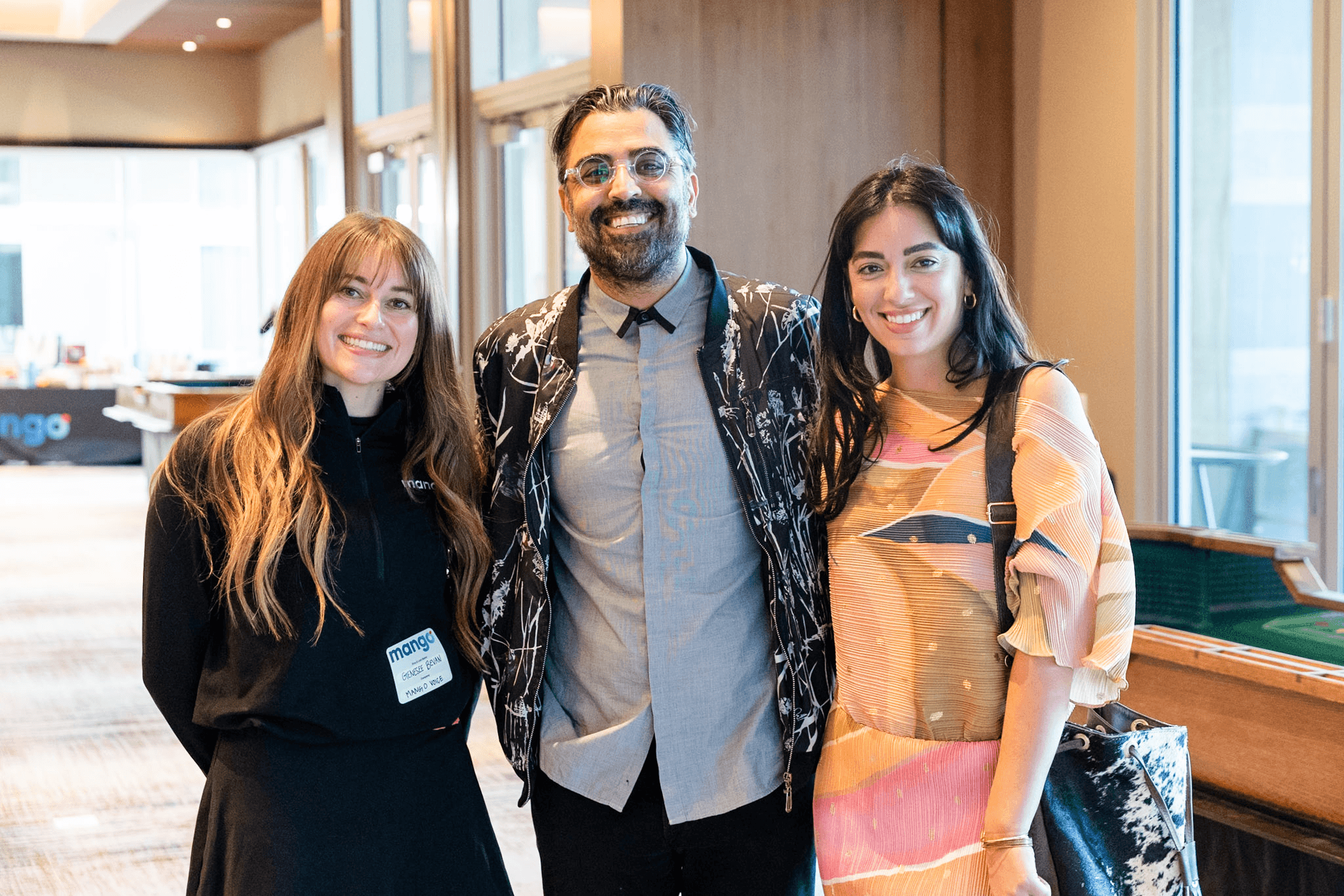 Three attendees smiling together at the Mango event