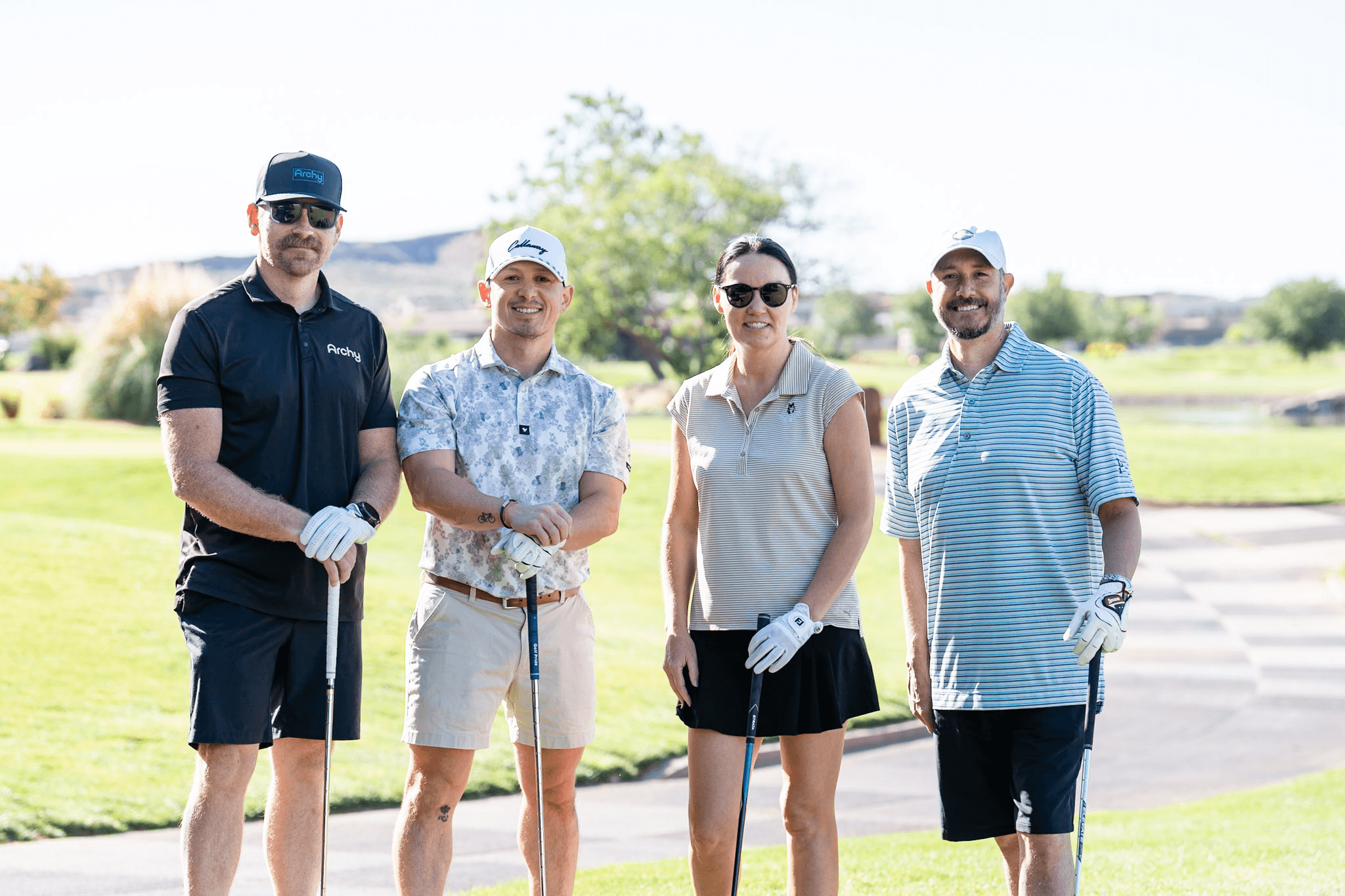 A foursome posing with their clubs on the course